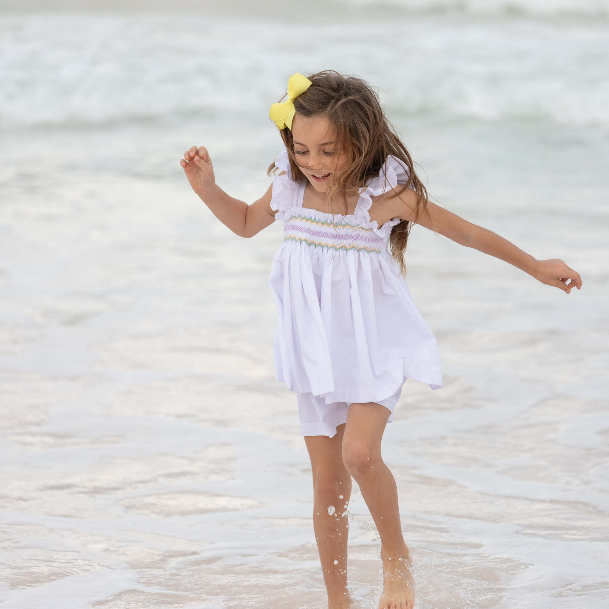 Henry Duvall girls smocked shorts set in Classic White, a classic two-piece outfit with flutter sleeves and blue embroidered smocking.