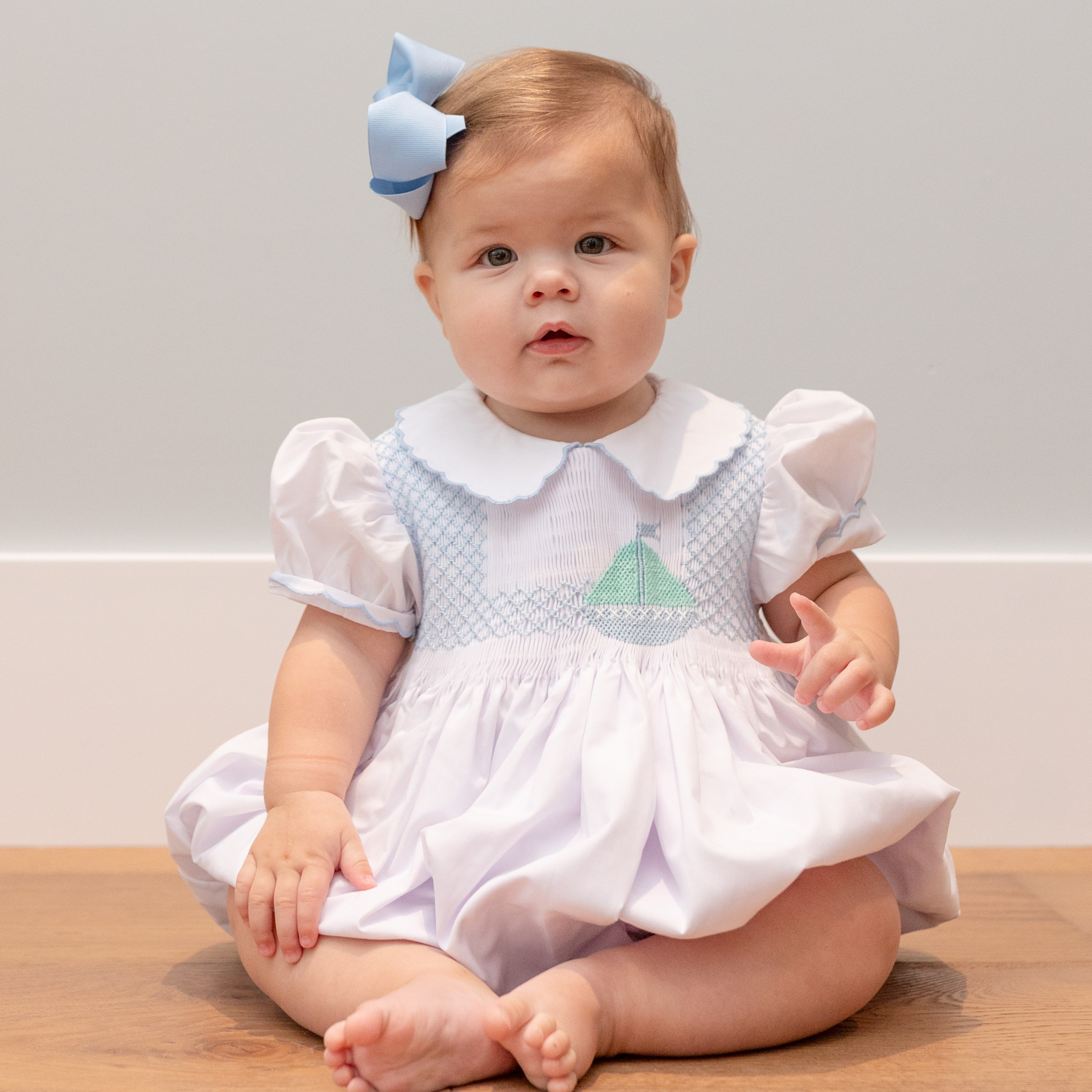 Henry Duvall Eloise Bubble in white cotton with Bailey’s Bay Blue trim and hand-smocked sailboats, classic heirloom baby girl summer outfit with scalloped Peter Pan collar
