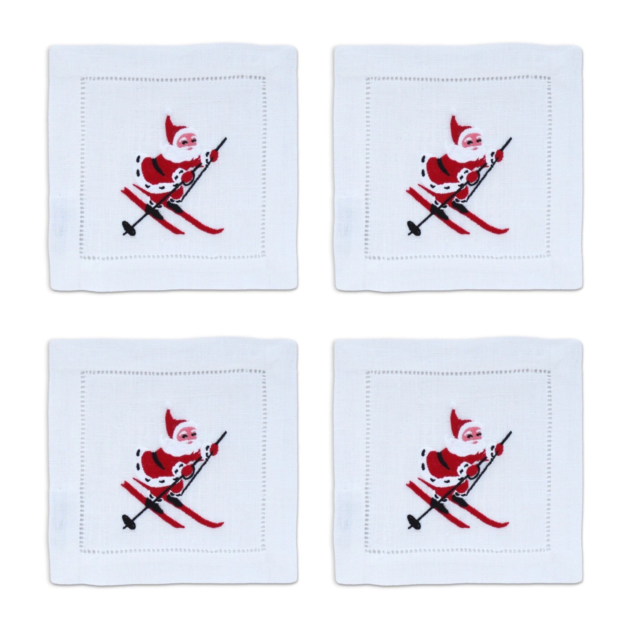 Four white cotton cocktail napkins featuring a red and black embroidered skiing Santa design.