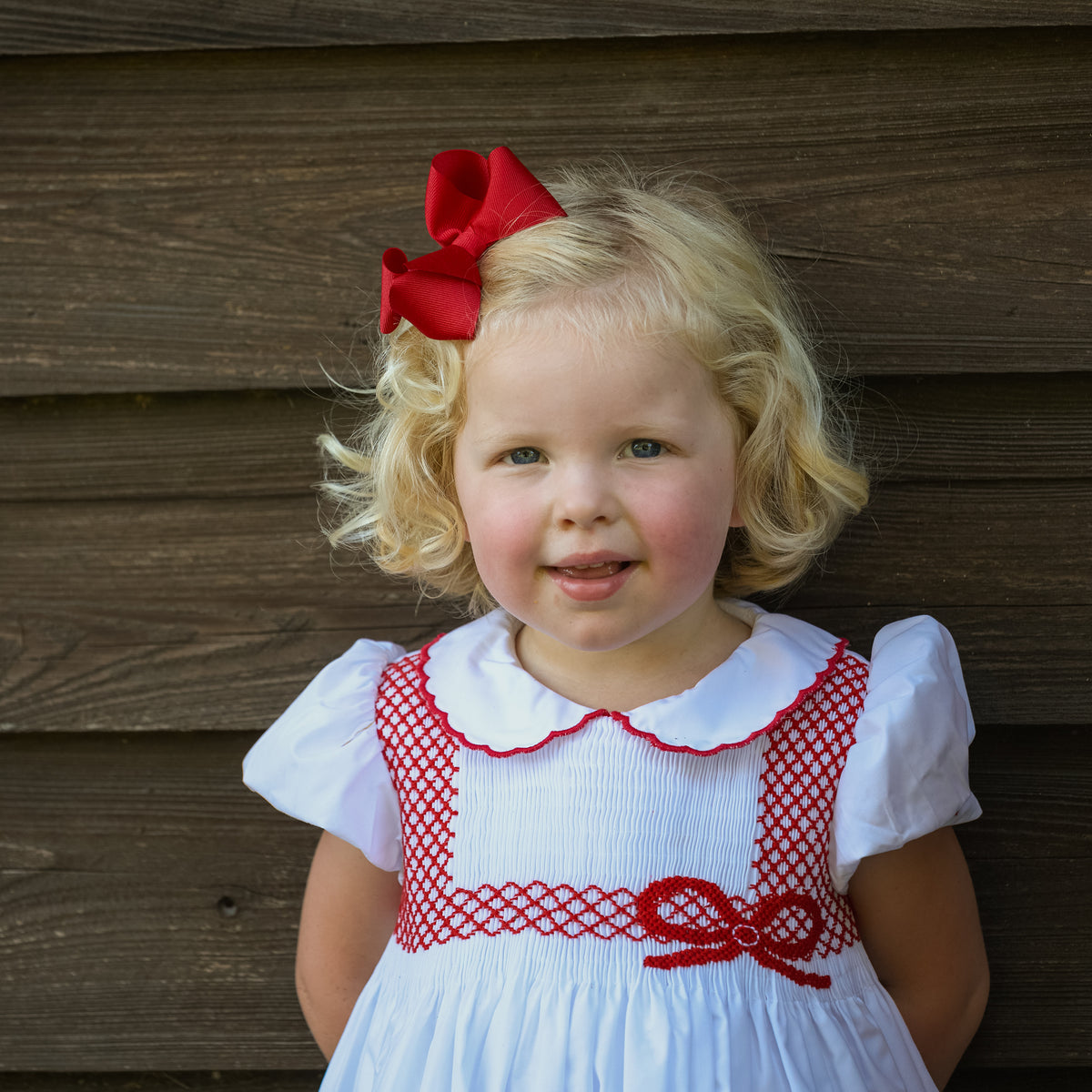 White short sleeve baby girl holiday bubble with red smocked bows, Peter Pan collar, and piped cuffs, classic Eloise Bubble by Henry Duvall for Christmas and winter celebrations