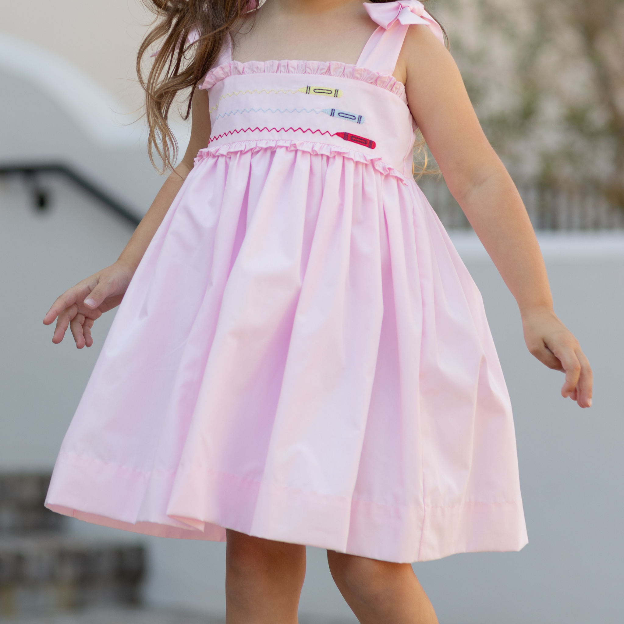 Henry Duvall Daisy Dress in blush pink cotton with hand-smocked crayon embroidery and shoulder bow ties, classic girls back-to-school dress for first day of school photos and fall occasions.