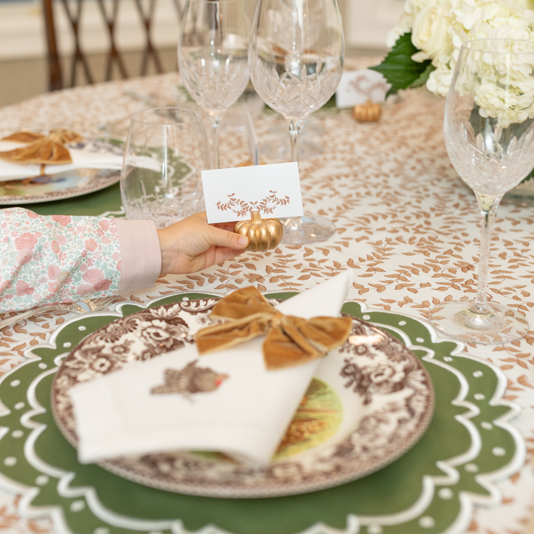Gold pumpkin-shaped place card holder on a fall-themed table setting.