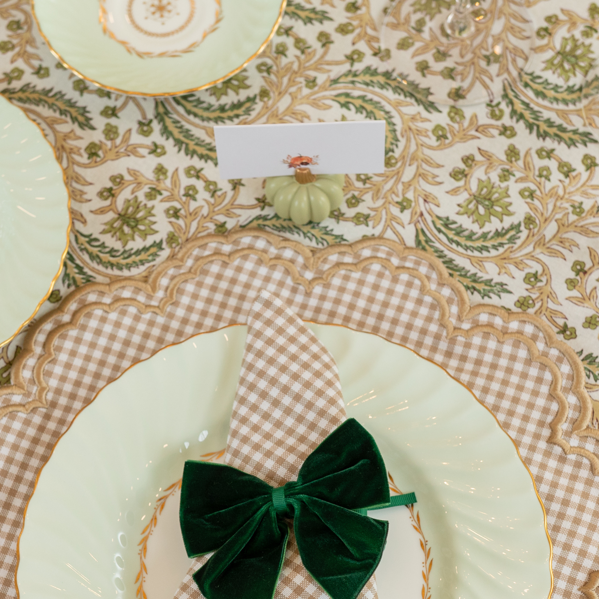 Sage green pumpkin-shaped place card holder on a fall-themed table setting.