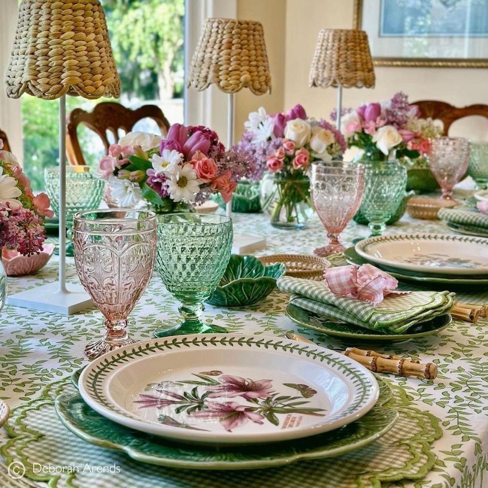 Elegant dining table setting with floral plates, glasses, and centerpieces.