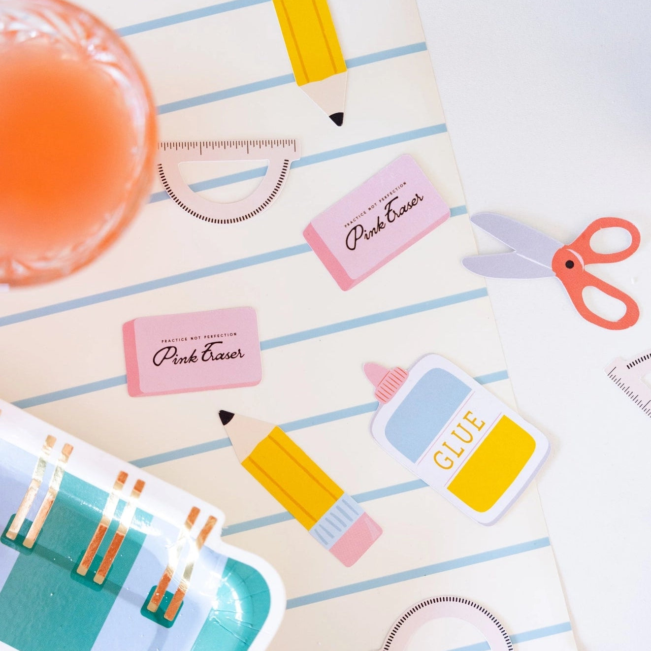 Colorful stationery items including a pencil, glue stick, and scissors on a striped background.