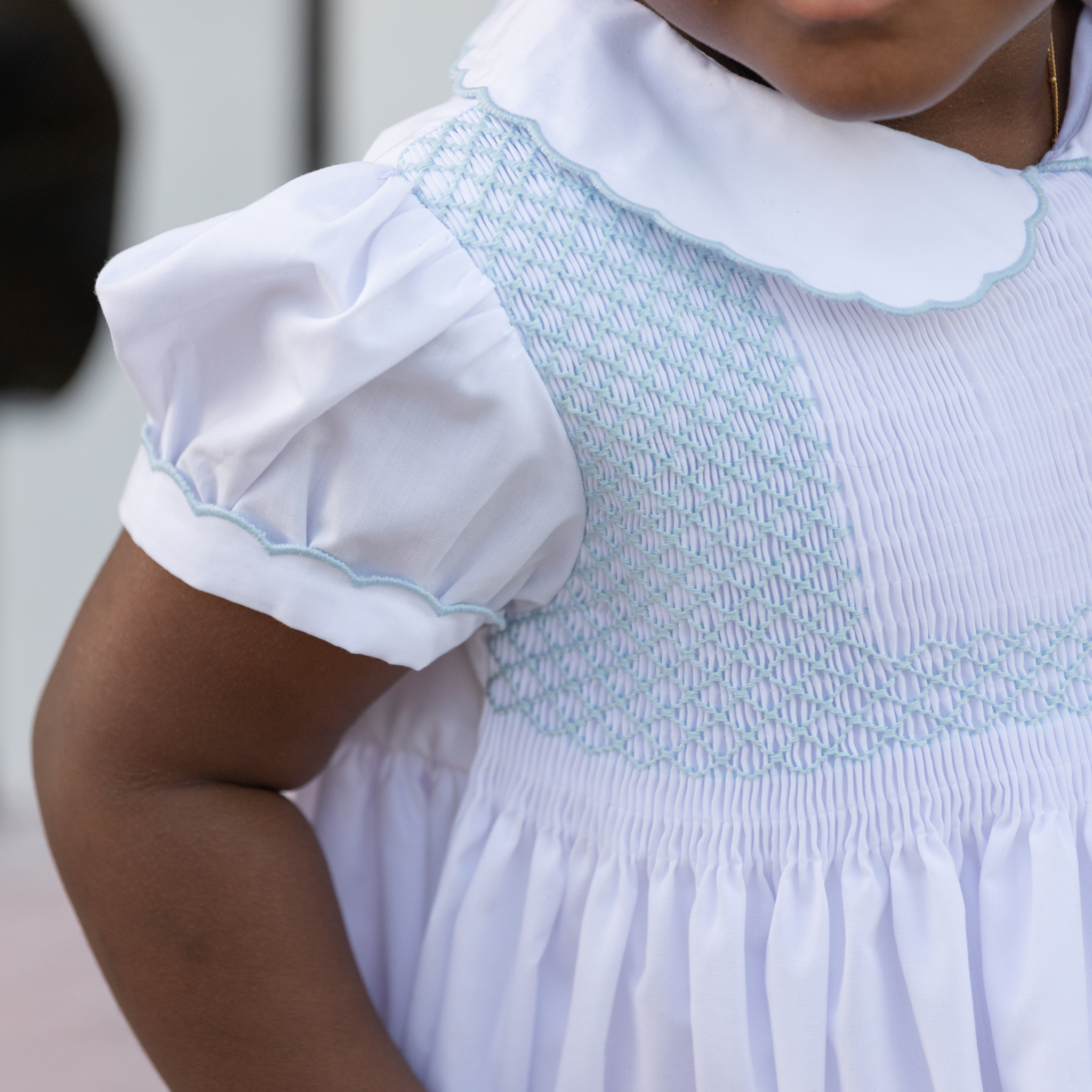 Henry Duvall Eloise Dress in white cotton with Bailey’s Bay Blue trim and hand-smocked sailboats, classic heirloom baby girl summer outfit with scalloped Peter Pan collar