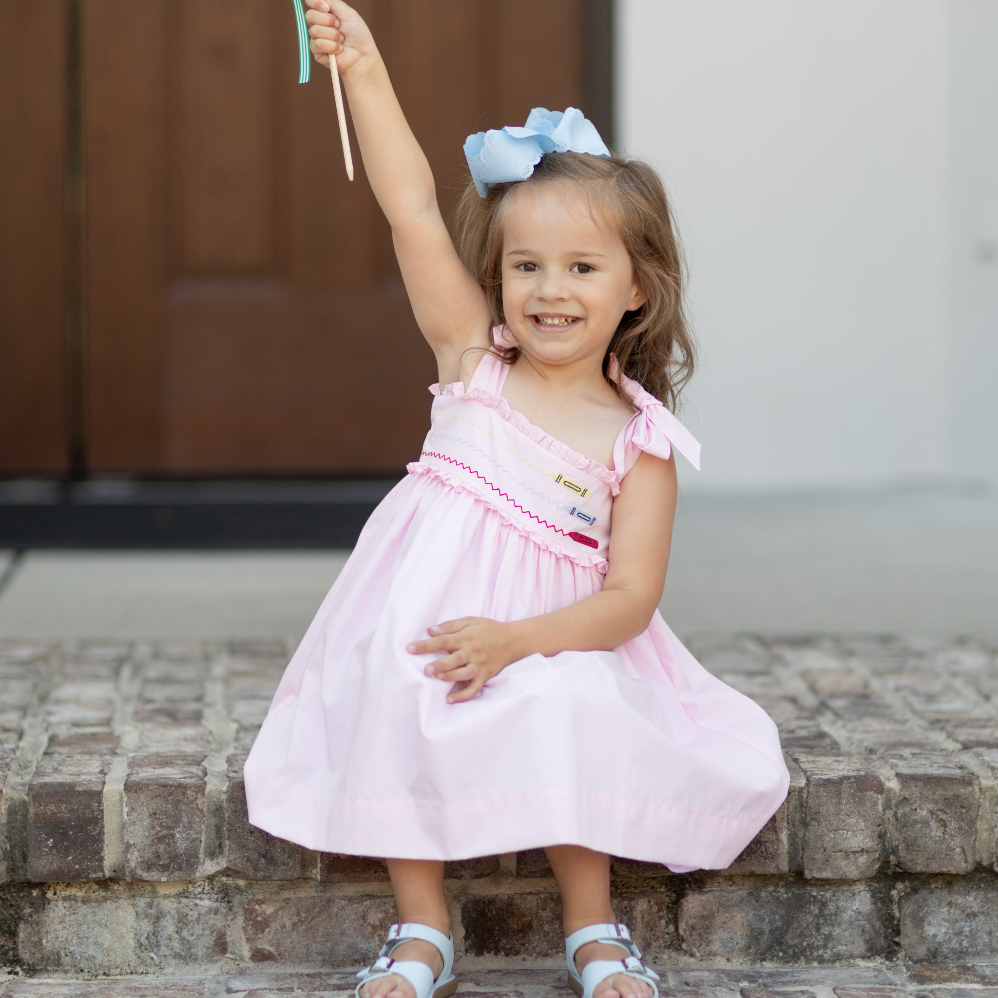 Henry Duvall Daisy Dress in blush pink cotton with hand-smocked crayon embroidery and shoulder bow ties, classic girls back-to-school dress for first day of school photos and fall occasions.