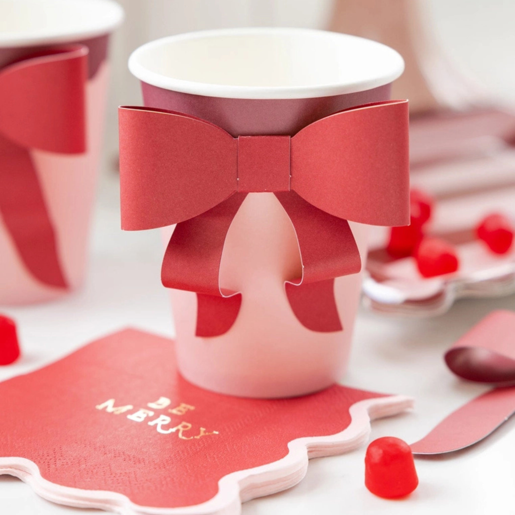 Red and pink paper party cup with a large red paper bow attached to the front, perfect for festive holiday gatherings.
