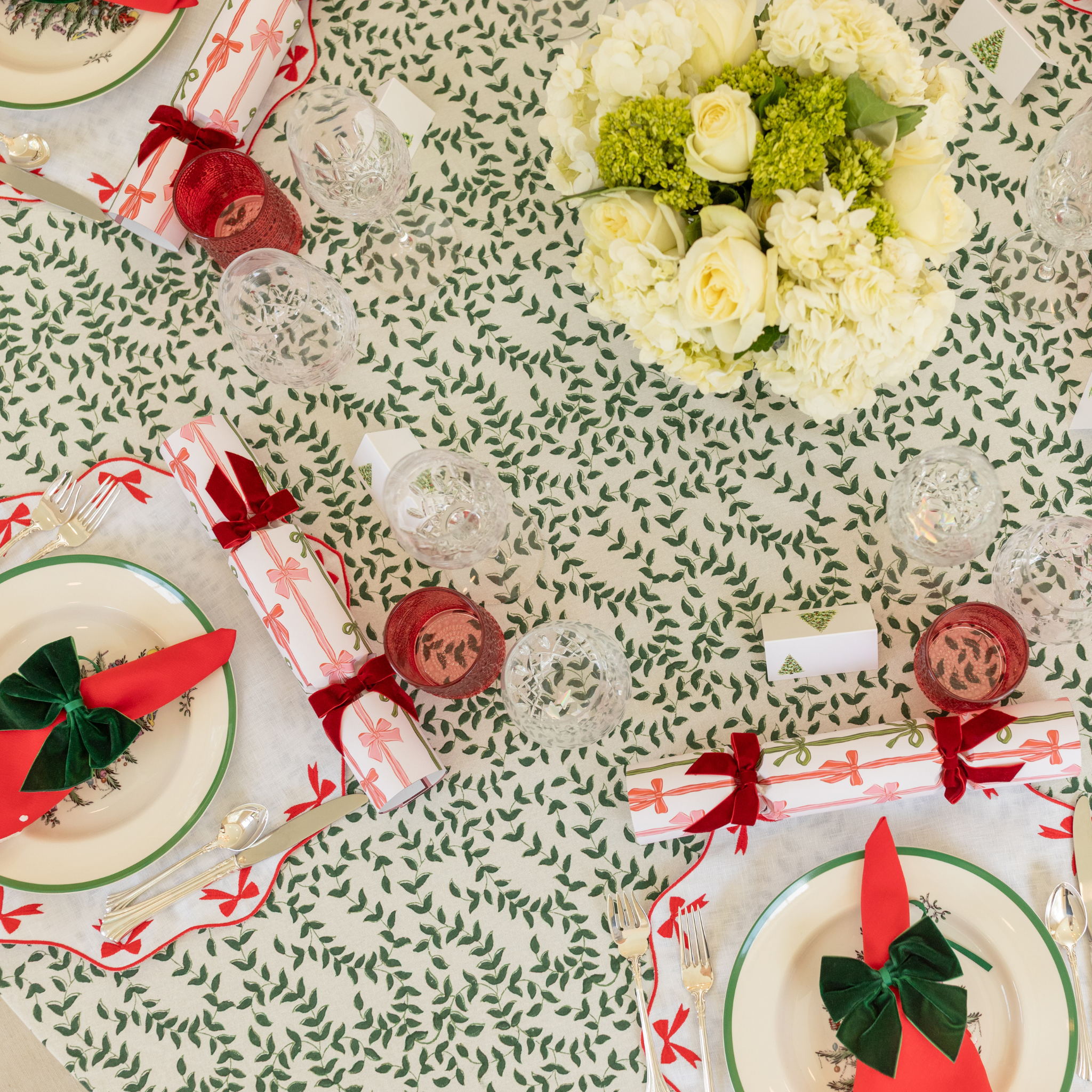 White linen placemat with scalloped edges and red embroidered bows, styled for holiday tabletop decor.