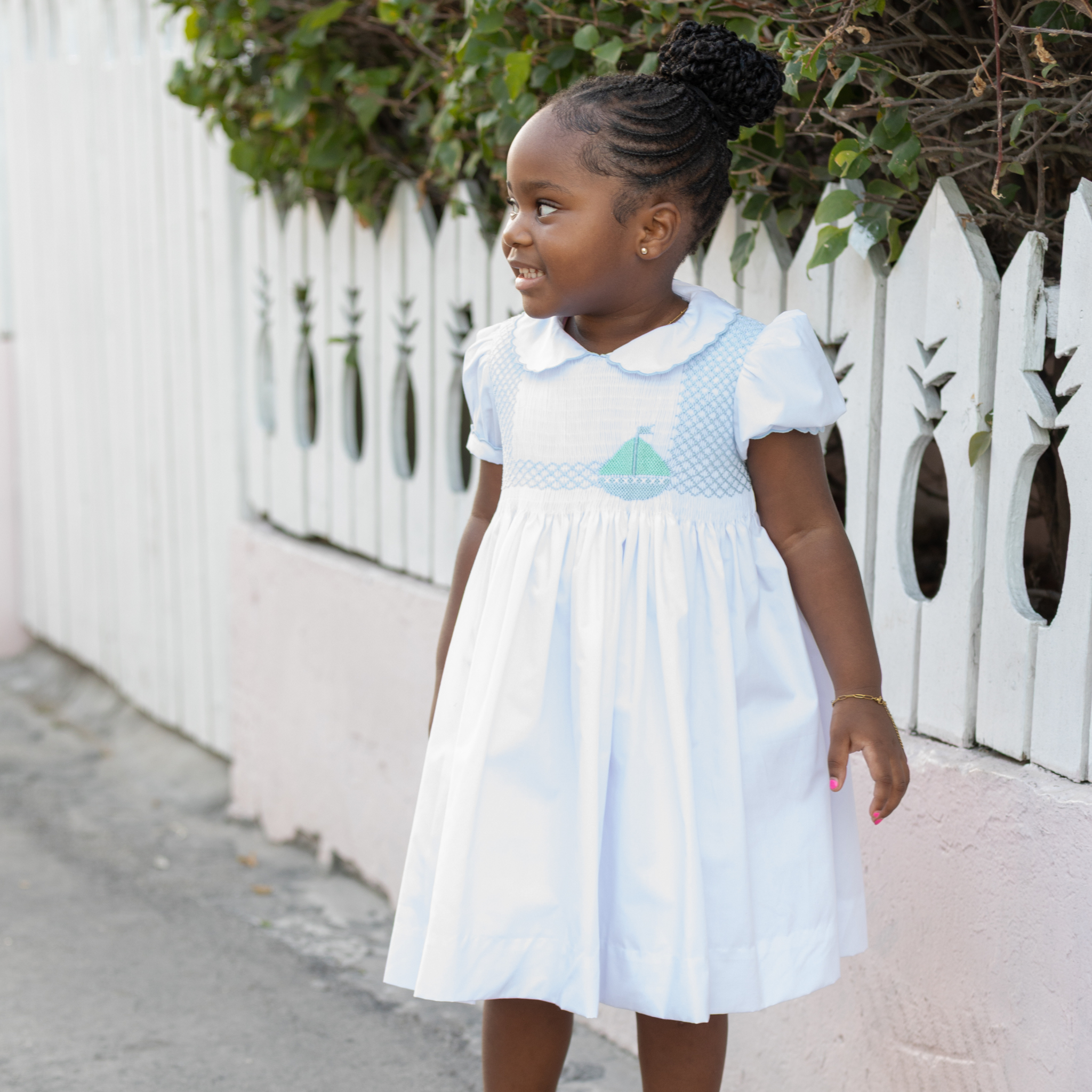 Henry Duvall Eloise Dress in white cotton with Bailey’s Bay Blue trim and hand-smocked sailboats, classic heirloom baby girl summer outfit with scalloped Peter Pan collar