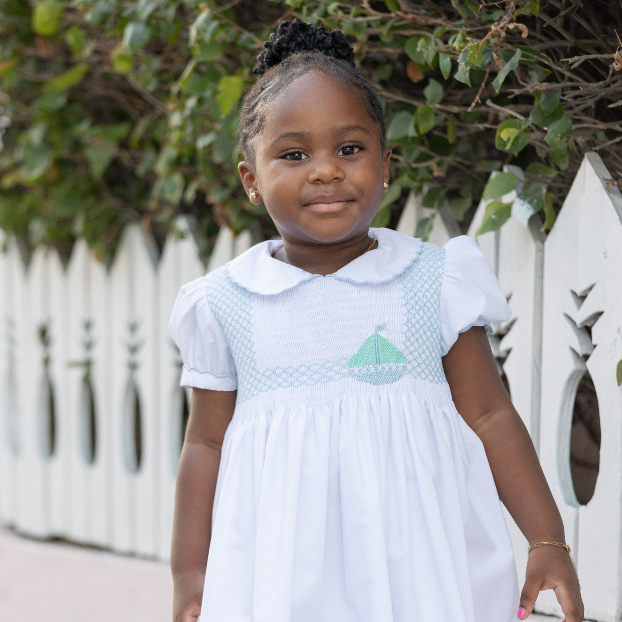 Henry Duvall Eloise Dress in white cotton with Bailey’s Bay Blue trim and hand-smocked sailboats, classic heirloom baby girl summer outfit with scalloped Peter Pan collar
