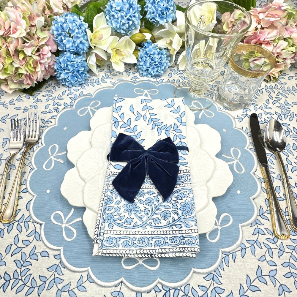 Decorative table setting with blue and white floral patterns, a navy bow, and silverware.