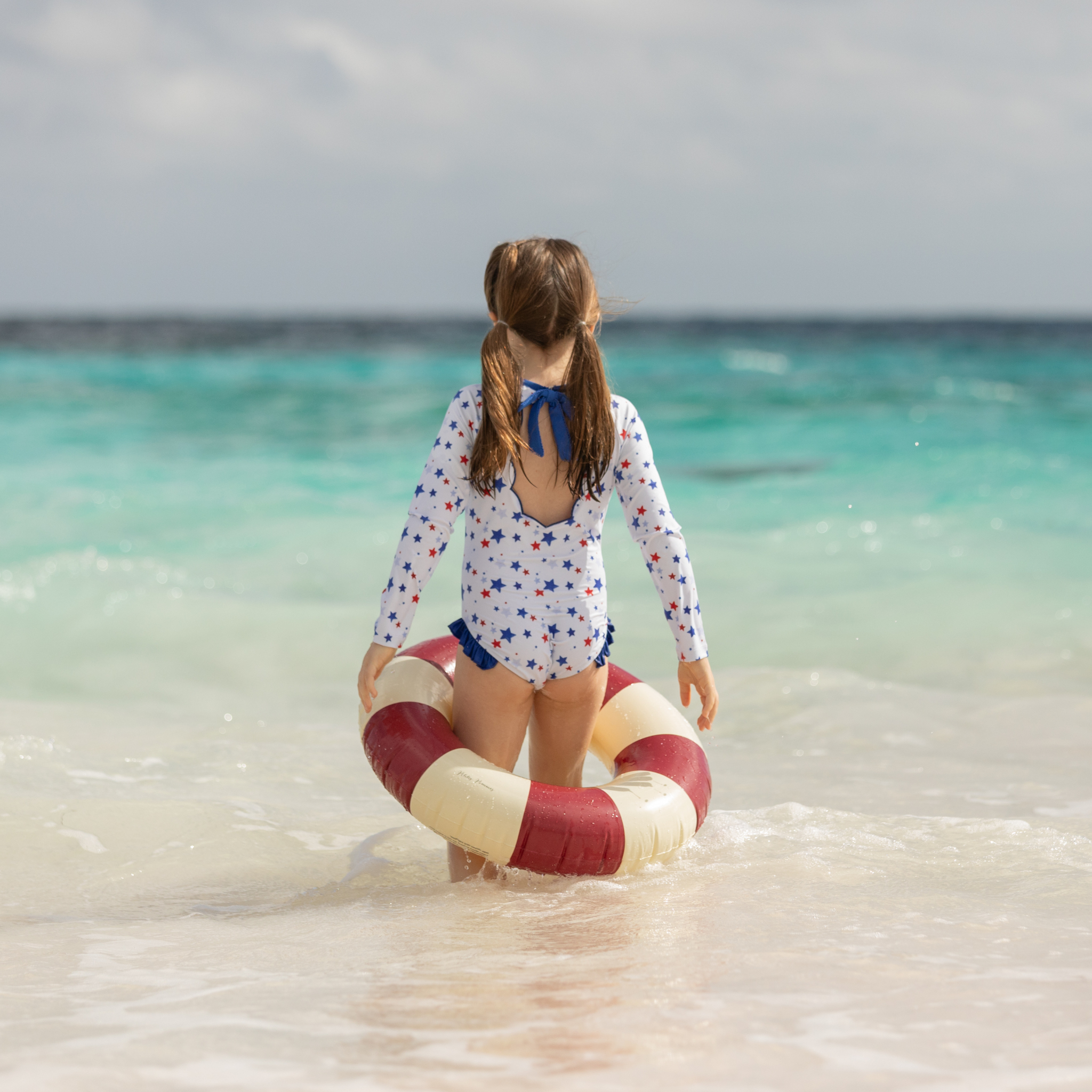 Henry Duvall Reese girls rashguard one piece in red white and blue star print, UPF 50+ long sleeve swimsuit for 4th of July, beach, and summer holidays