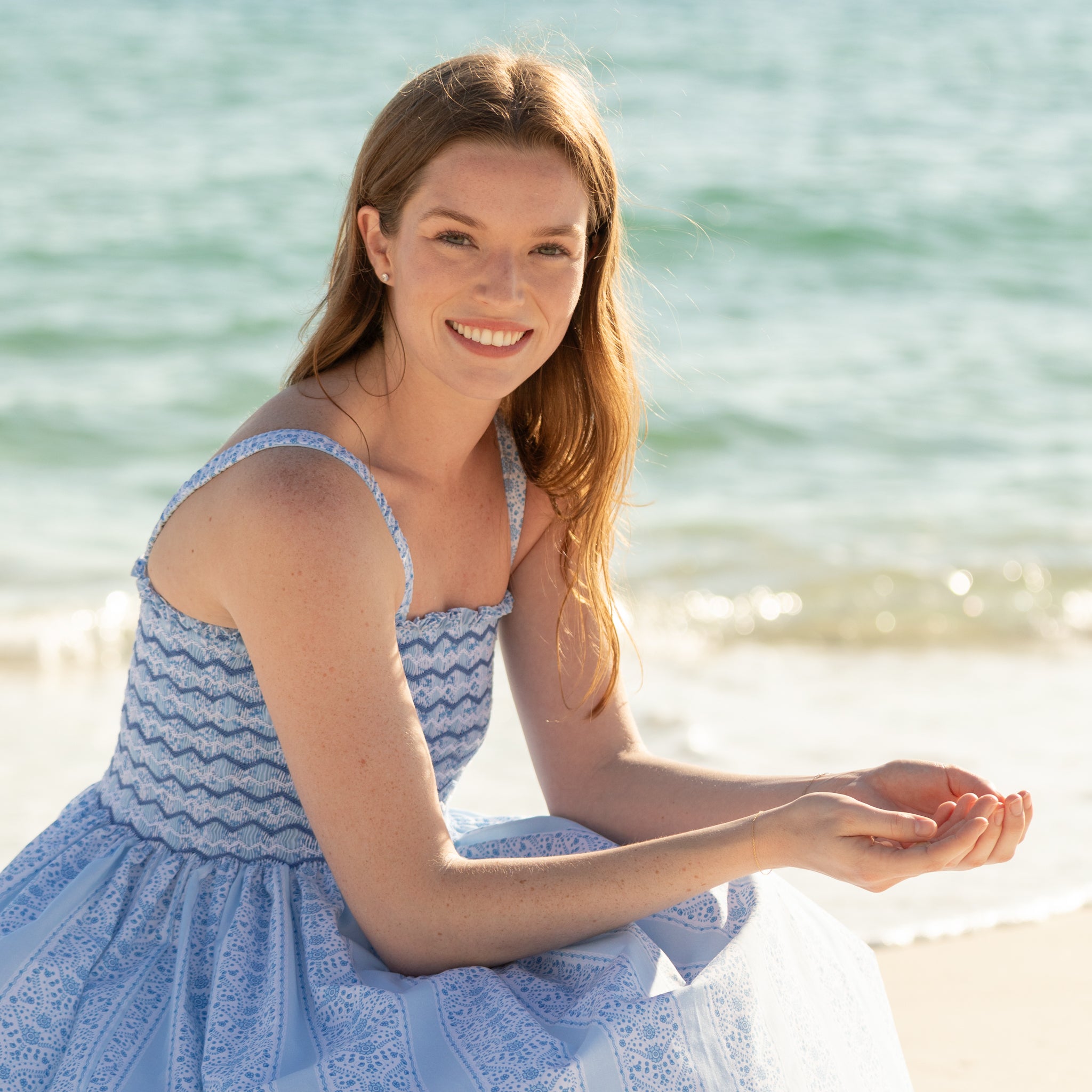 Woman walking along the beach wearing the Henry Duvall Kate Dress, a breezy striped women’s dress with coastal style.