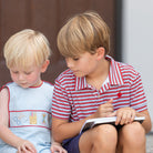 Henry Duvall Jennings Jon Jon with back-to-school embroidery, classic blue toddler boys romper with red trim and heirloom stitching of crayons, scissors, pencils, and ruler