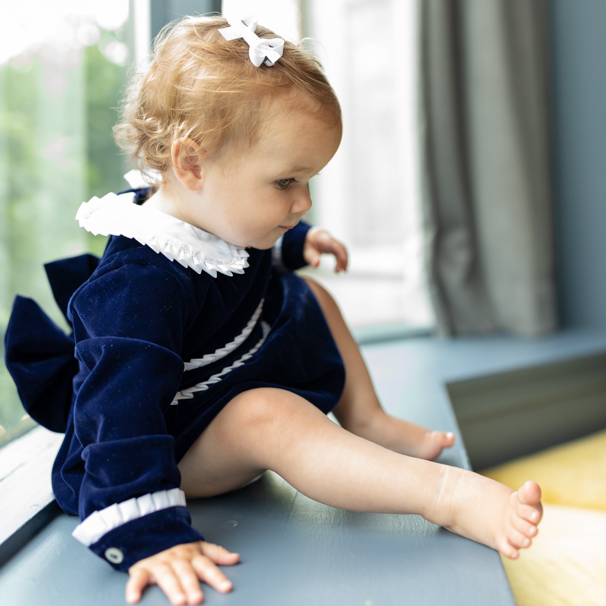 Baby girls navy velvet bubble with white pleated detailing and pre-tied bow, long sleeve fall outfit for special occasions and family photos by Henry Duvall