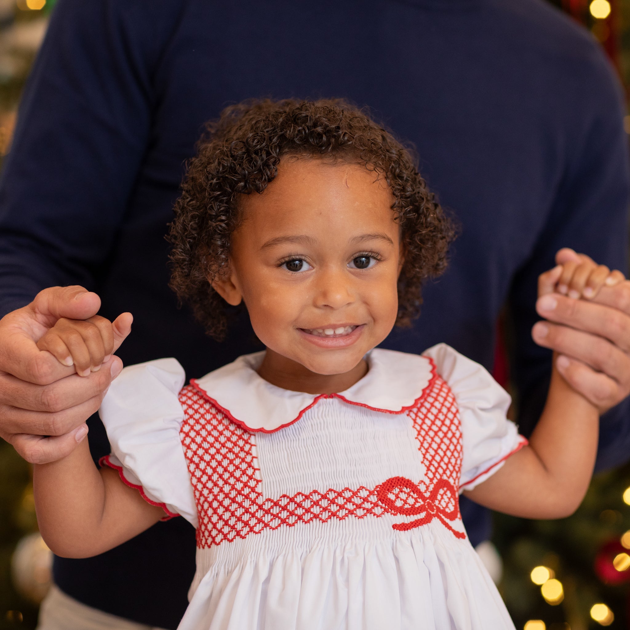 White short sleeve baby girl holiday bubble with red smocked bows, Peter Pan collar, and piped cuffs, classic Eloise Bubble by Henry Duvall for Christmas and winter celebrations