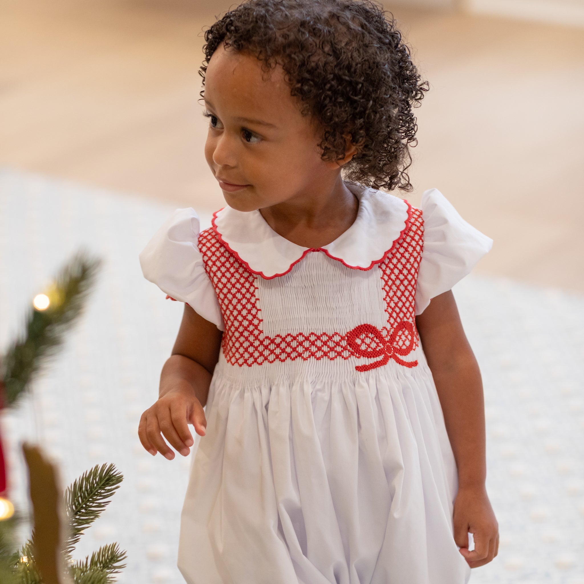 White short sleeve baby girl holiday bubble with red smocked bows, Peter Pan collar, and piped cuffs, classic Eloise Bubble by Henry Duvall for Christmas and winter celebrations
