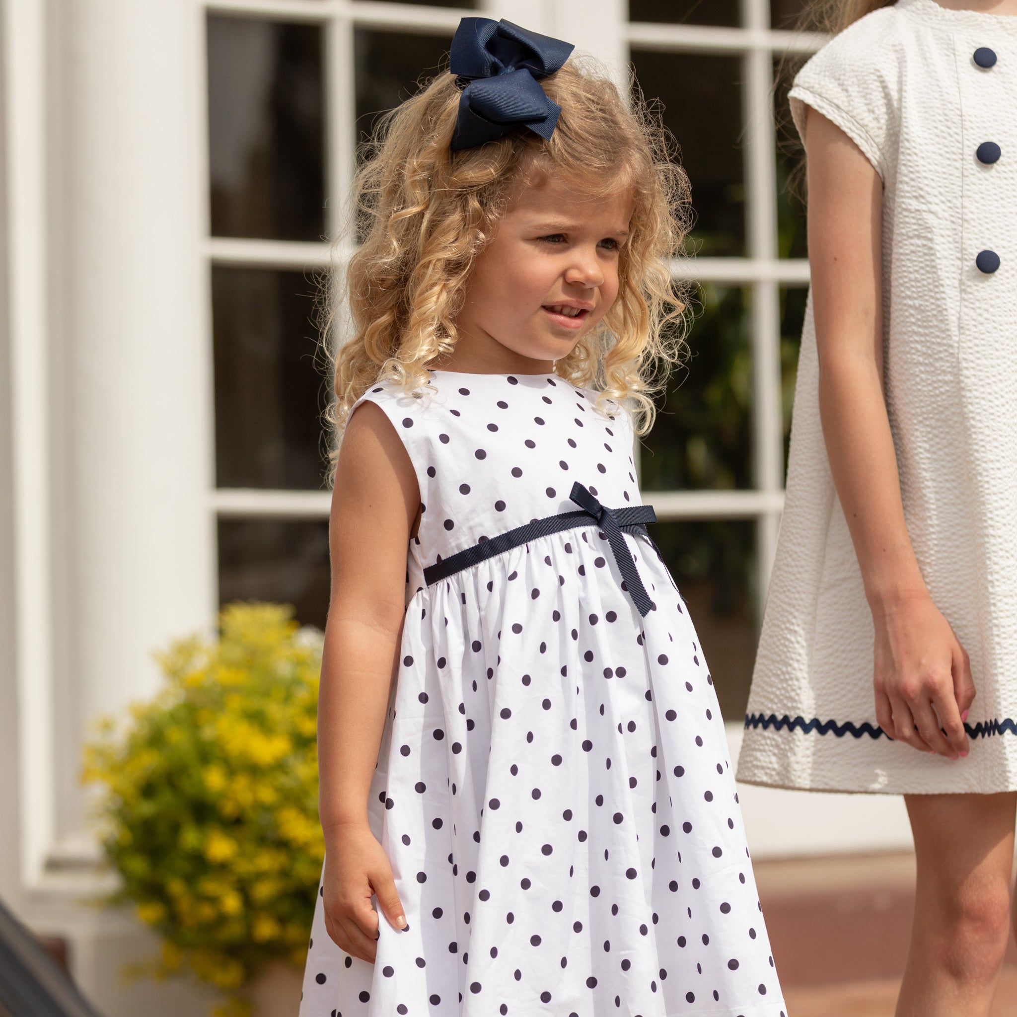 Henry Duvall Betsy Dress in white cotton with navy polka dots and grosgrain bow, classic twirl dress for girls that transitions from summer to fall