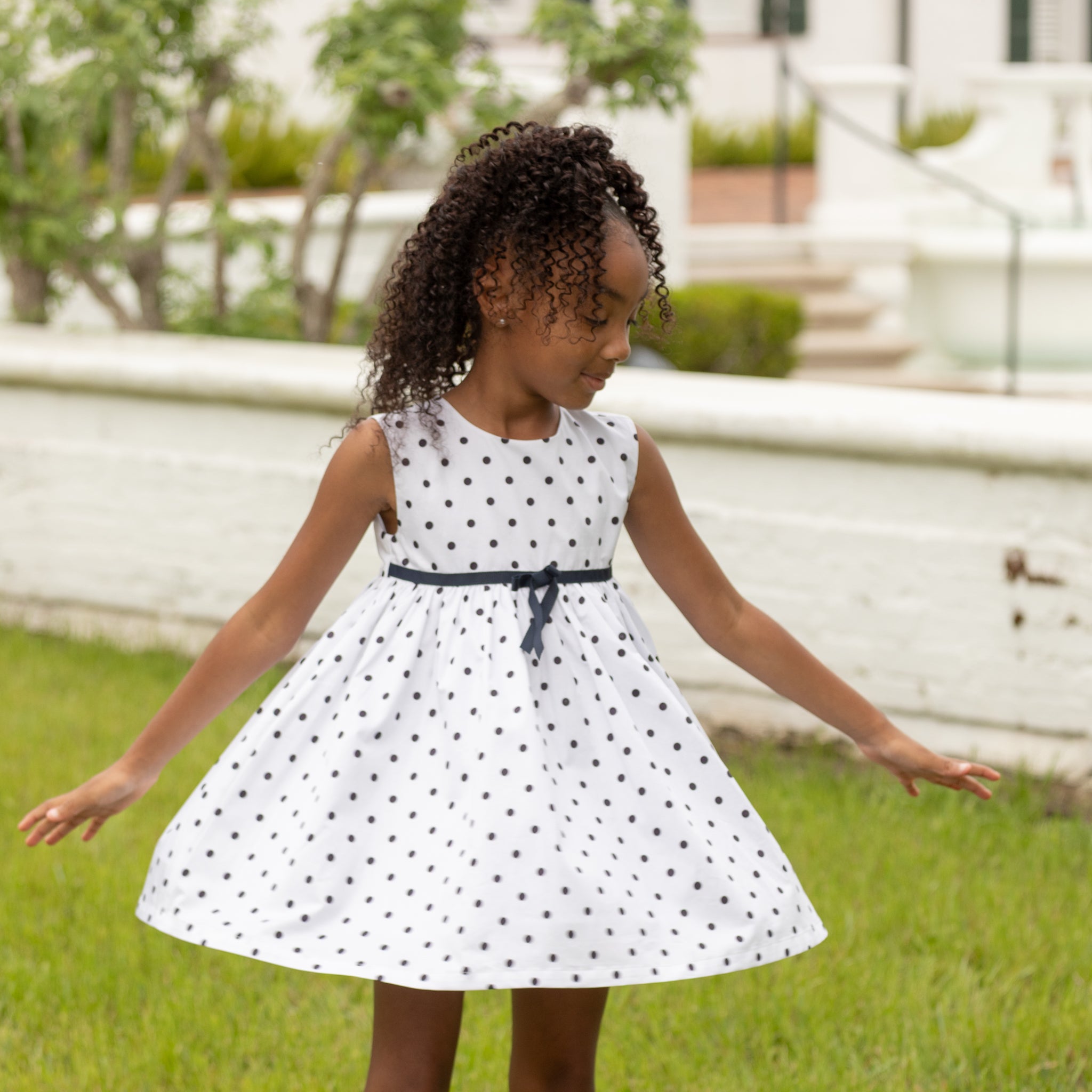 Henry Duvall Betsy Dress in white cotton with navy polka dots and grosgrain bow, classic twirl dress for girls that transitions from summer to fall