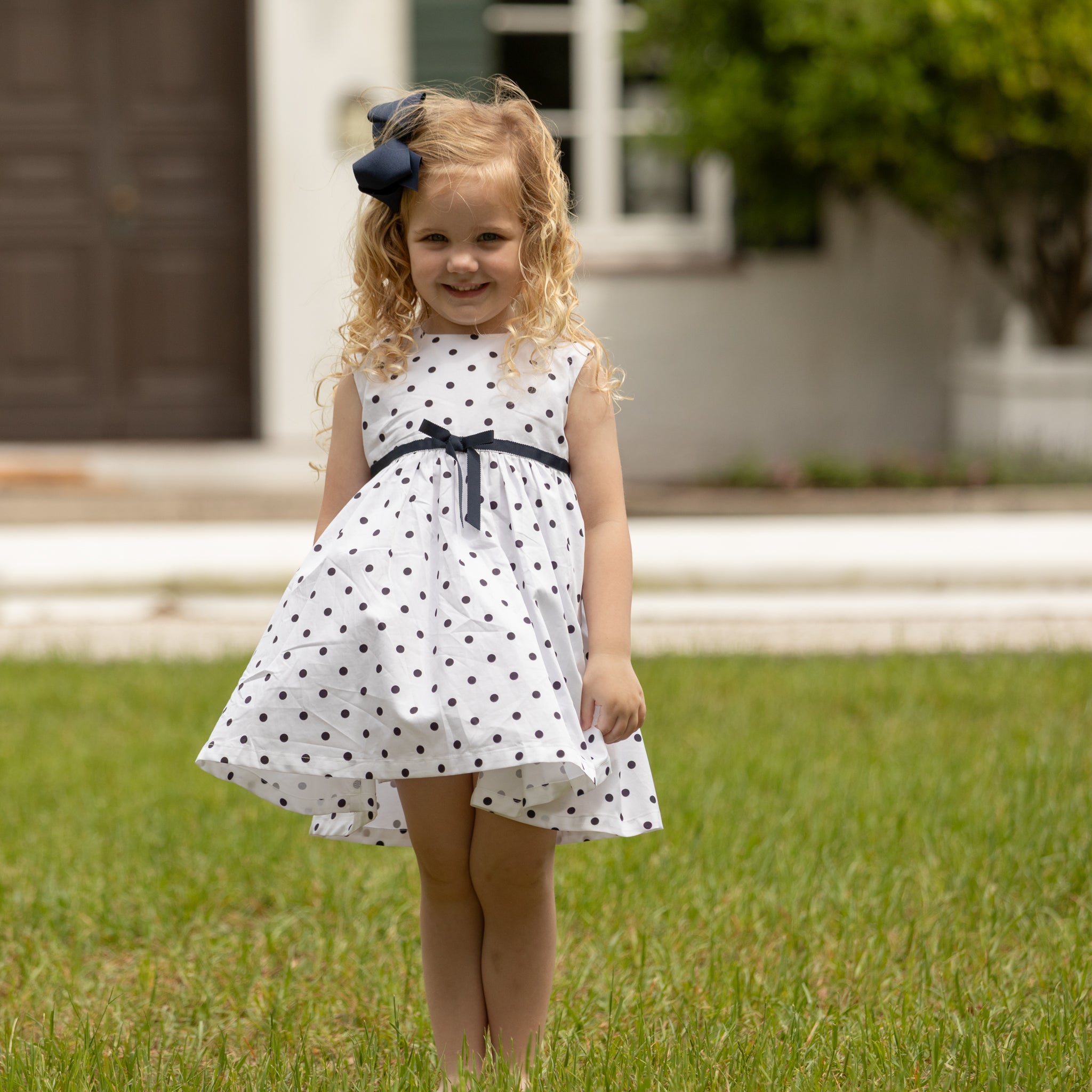 Henry Duvall Betsy Dress in white cotton with navy polka dots and grosgrain bow, classic twirl dress for girls that transitions from summer to fall