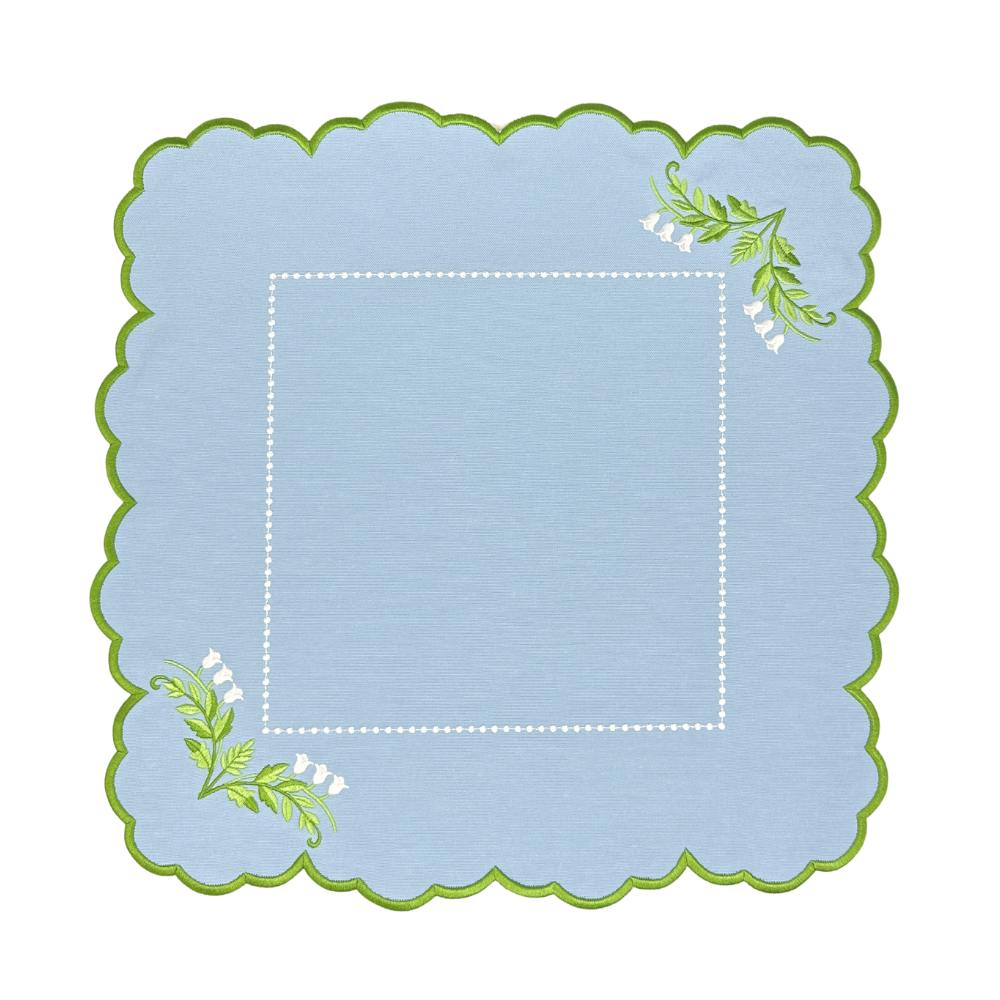 Decorative blue placemat with green scalloped edge and floral designs on a white background