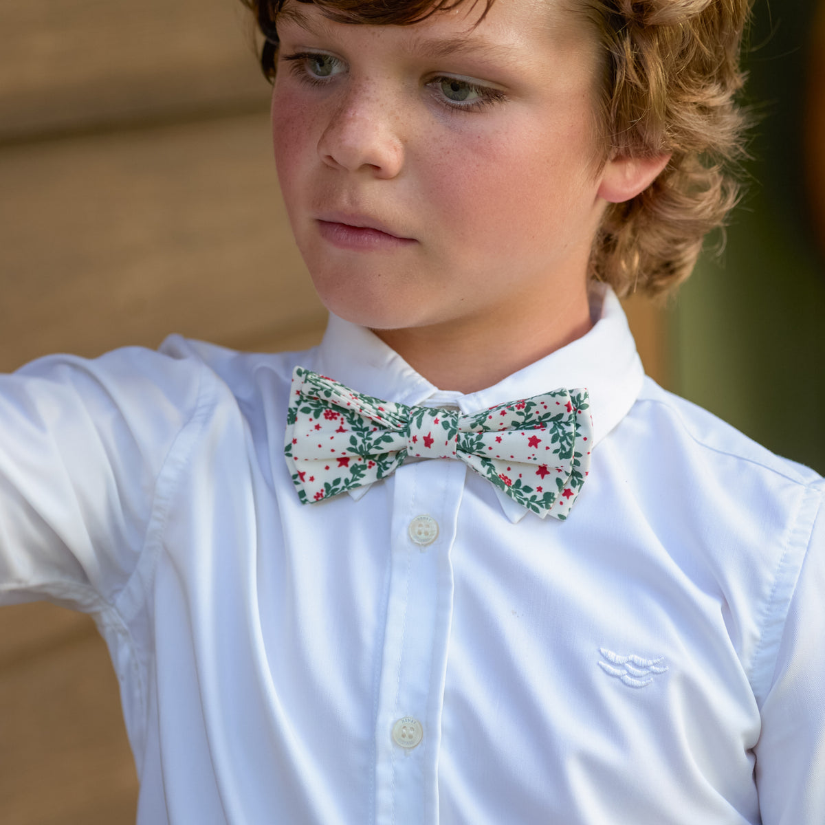 Boys’ Baker Bow Tie in Regent Wreaths, a festive red and green holiday print on a classic white background.