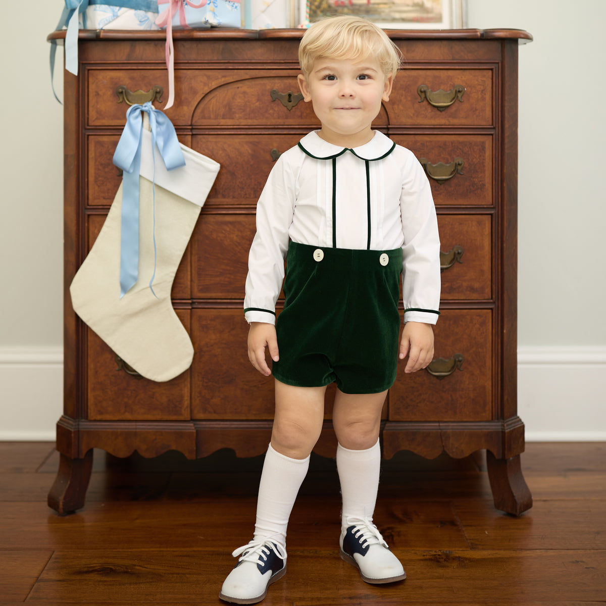 Boys’ Benjamin Button On with crisp white long-sleeve cotton poplin top, Grafton Green piping and pintuck details, paired with Grafton Green Velvet shorts and signature HD buttons.