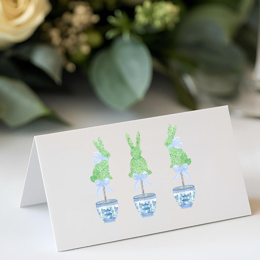 Card with illustrations of potted plants on a white surface with flowers in the background