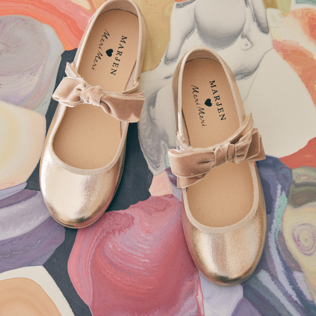 Meri Meri x Marjen Missy metallic gold Mary Jane with velvet bow, pair on a painterly background