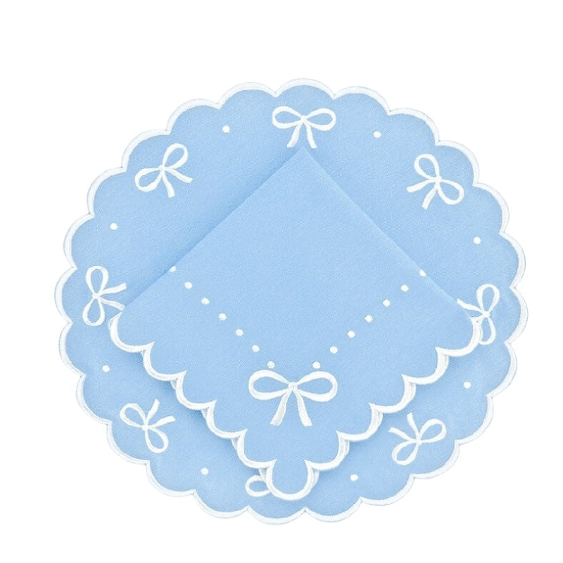 Light blue doily with white scalloped edges and bow designs on a white background