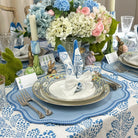Easter table setting with floral centerpieces, bunny decorations, and patterned tablecloth.
