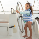 Girls’ long sleeve rashguard one piece swimsuit in Seaside Seersucker with UPF 50+ and scalloped open back, perfect for summer or beach vacations by Henry Duvall.