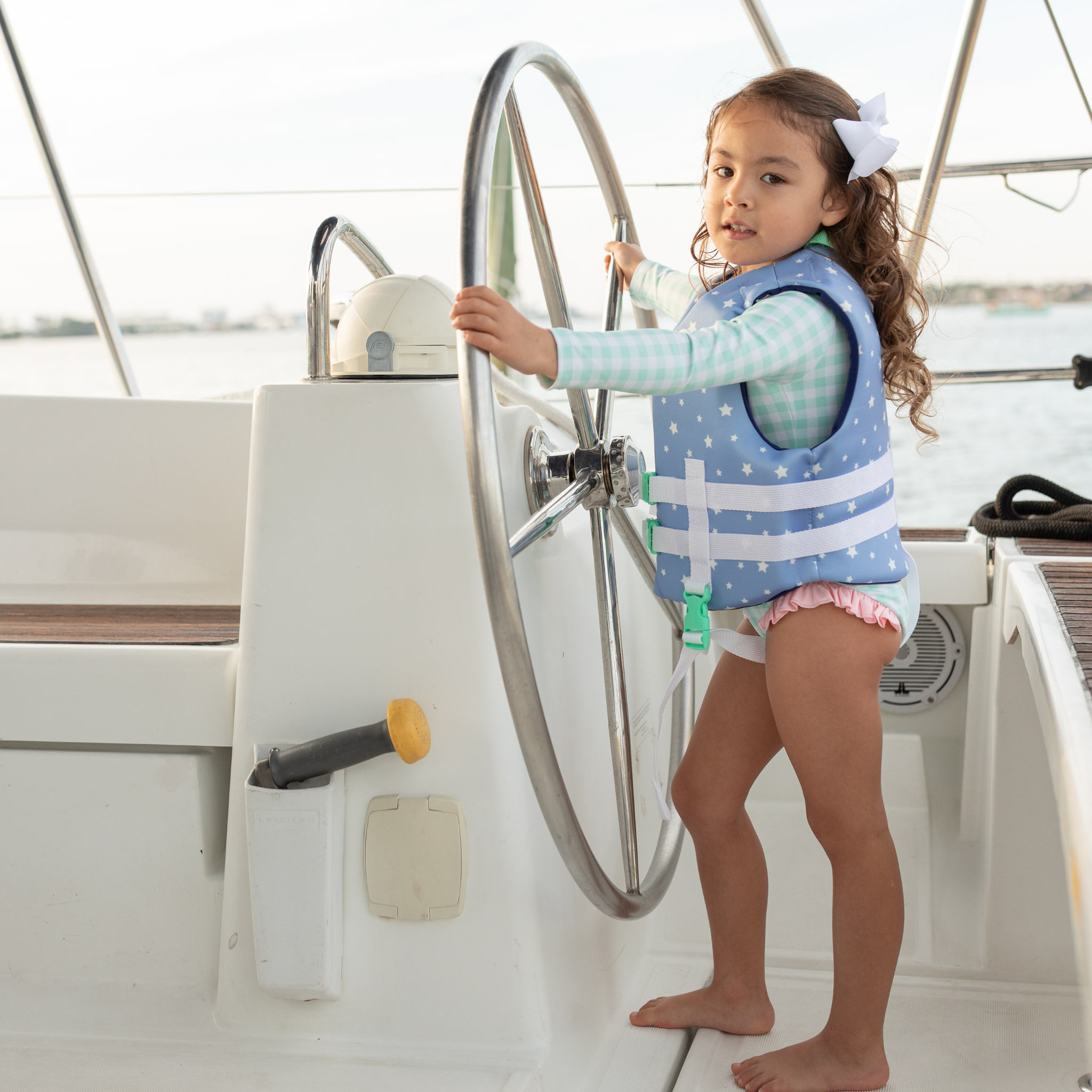 Girls’ long sleeve rashguard one piece swimsuit in Seaside Seersucker with UPF 50+ and scalloped open back, perfect for summer or beach vacations by Henry Duvall.