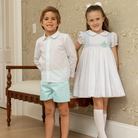 Henry Duvall Eloise Dress in white cotton with Bailey’s Bay Blue trim and hand-smocked sailboats, classic heirloom baby girl summer outfit with scalloped Peter Pan collar