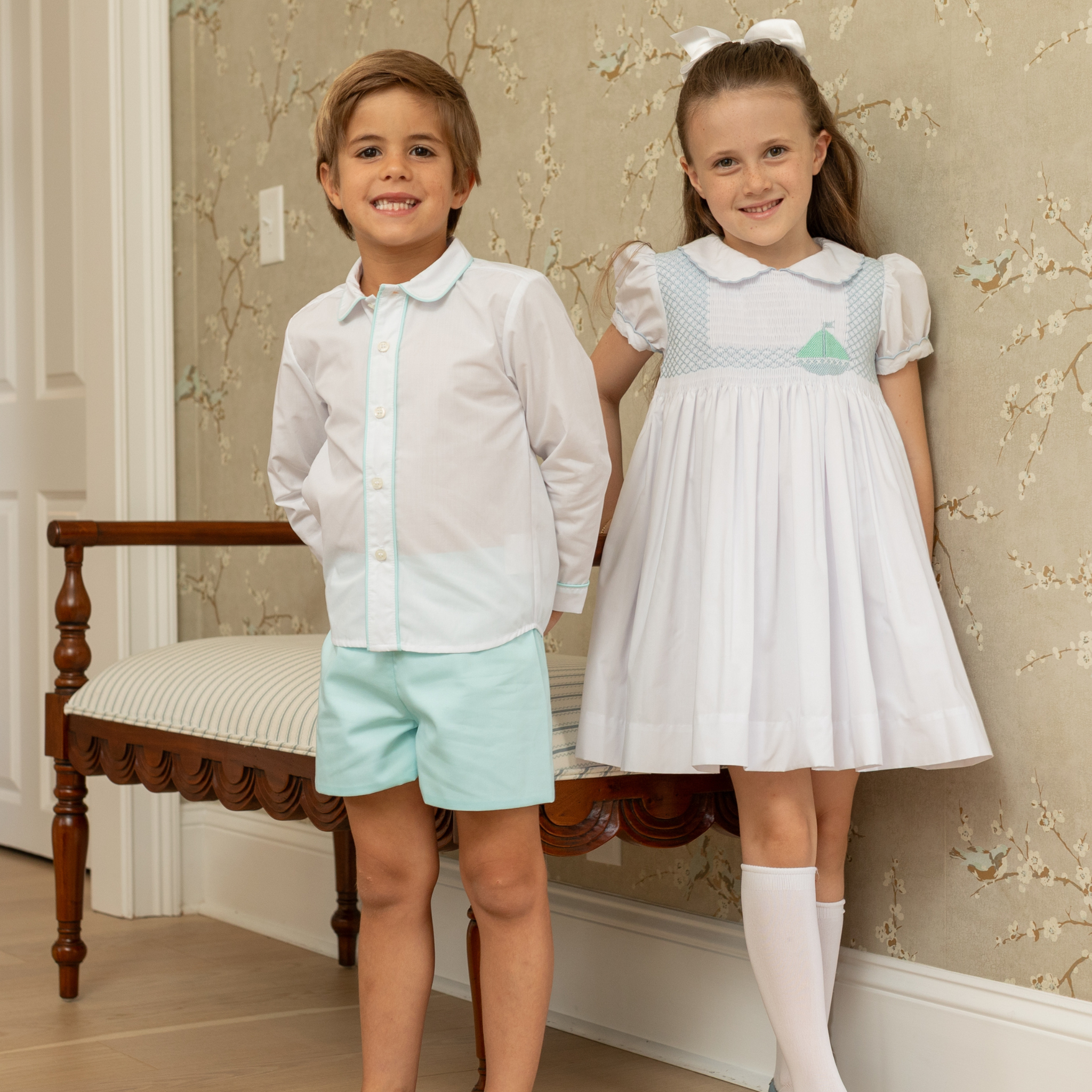Henry Duvall Eloise Dress in white cotton with Bailey’s Bay Blue trim and hand-smocked sailboats, classic heirloom baby girl summer outfit with scalloped Peter Pan collar