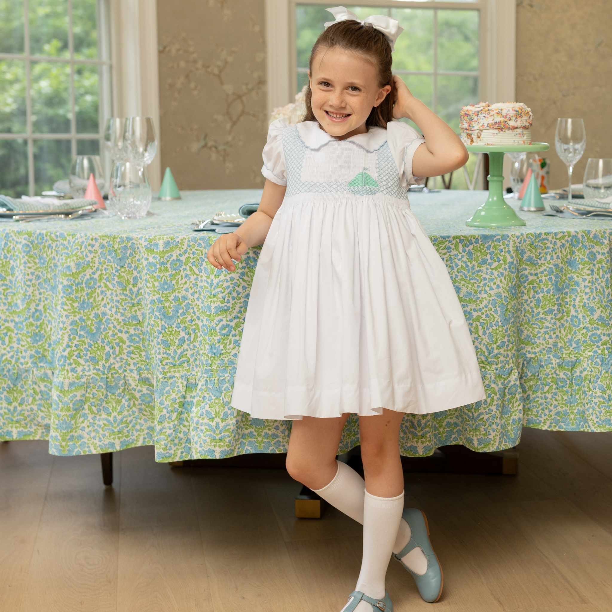 Henry Duvall Eloise Dress in white cotton with Bailey’s Bay Blue trim and hand-smocked sailboats, classic heirloom baby girl summer outfit with scalloped Peter Pan collar