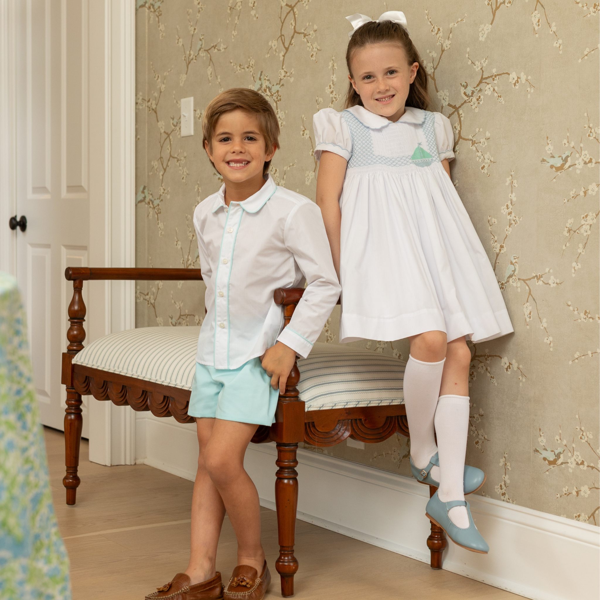 Henry Duvall Eloise Dress in white cotton with Bailey’s Bay Blue trim and hand-smocked sailboats, classic heirloom baby girl summer outfit with scalloped Peter Pan collar