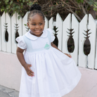 Henry Duvall Eloise Dress in white cotton with Bailey’s Bay Blue trim and hand-smocked sailboats, classic heirloom baby girl summer outfit with scalloped Peter Pan collar