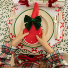 Red cloth napkin with white scalloped edge and embroidered dot detailing, styled for a festive holiday table setting.