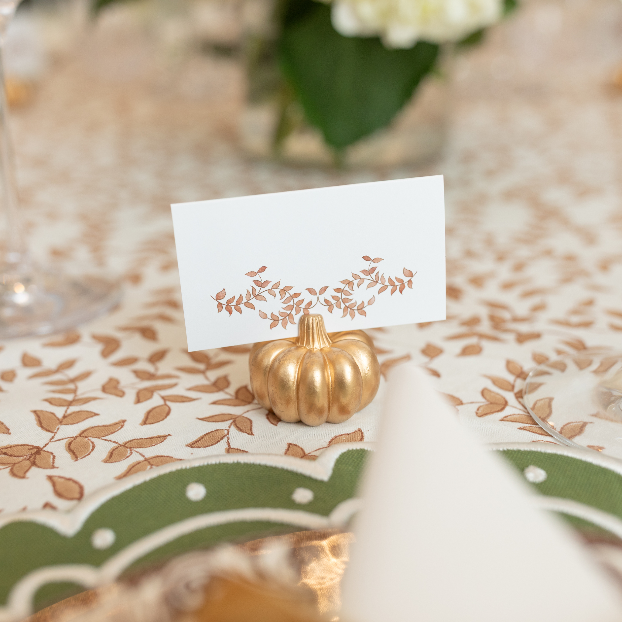 Gold pumpkin-shaped place card holder on a fall-themed table setting.