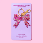Pink glitter bow keychain for girls, made of sparkly acrylic with a hand-sprinkled confetti finish; cute holiday stocking stuffer or gift accessory