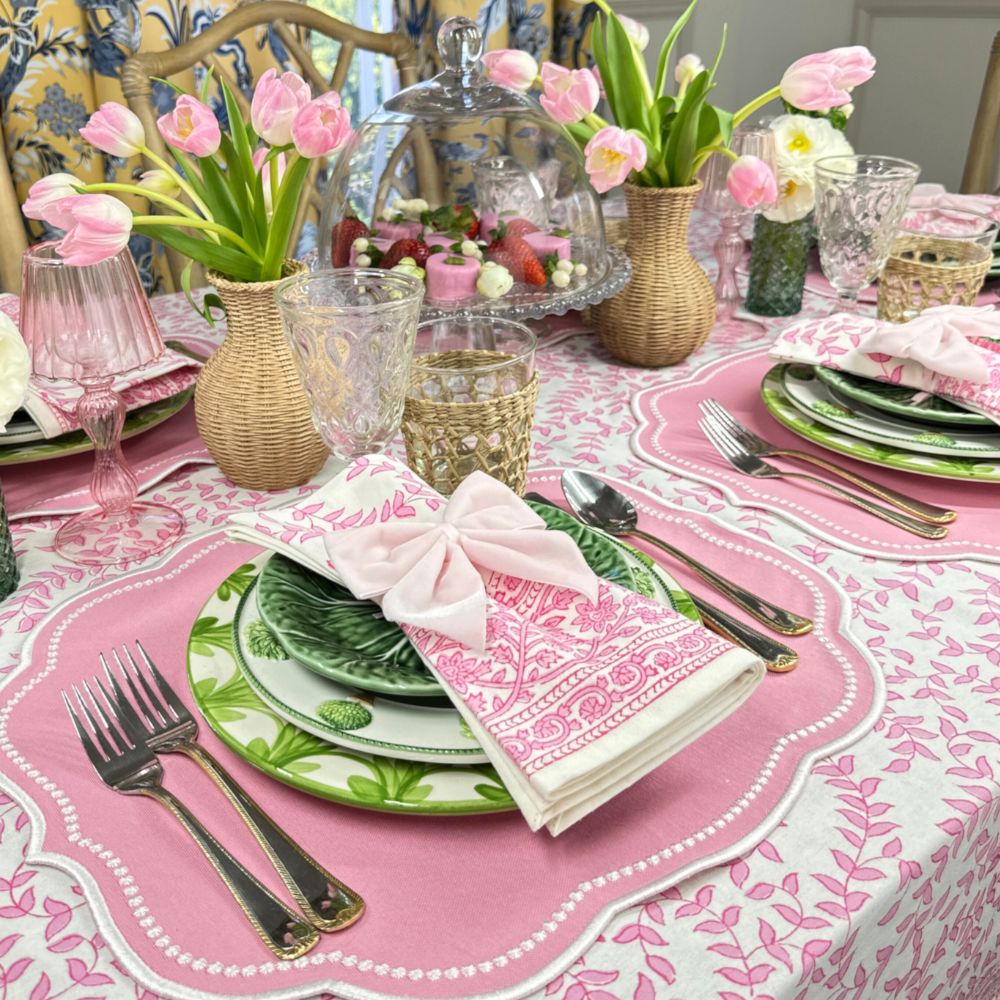 Easter table setting with pink and green decorations, including tulips and patterned tablecloth.