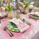 Easter table setting with pink and green decorations, including tulips and patterned tablecloth.