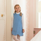 Henry Duvall Janie Jumper girls’ dress in Brookhaven Blue corduroy with scalloped hem and fabric-covered shoulder buttons, designed for layering with blouses and turtlenecks for fall.