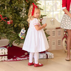 White short sleeve girls' holiday dress with red bow smocking across the chest, Peter Pan collar, and piped cuffs, classic Henry Duvall Eloise Dress for Christmas and winter family gatherings