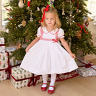 White short sleeve girls' holiday dress with red bow smocking across the chest, Peter Pan collar, and piped cuffs, classic Henry Duvall Eloise Dress for Christmas and winter family gatherings