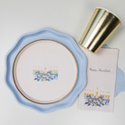 Hanukkah guest towel featuring a gold menorah with blue floral accents and “Happy Hanukkah” written in gold script on a soft blush background; ideal for festive holiday gatherings