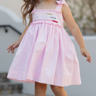 Henry Duvall Daisy Dress in blush pink cotton with hand-smocked crayon embroidery and shoulder bow ties, classic girls back-to-school dress for first day of school photos and fall occasions.