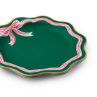 Holiday dinner plates with scalloped edges and red peppermint bow design in pink and green tones, perfect for festive Christmas table settings
